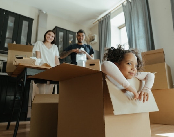 Little girl playing in a box while her parents look